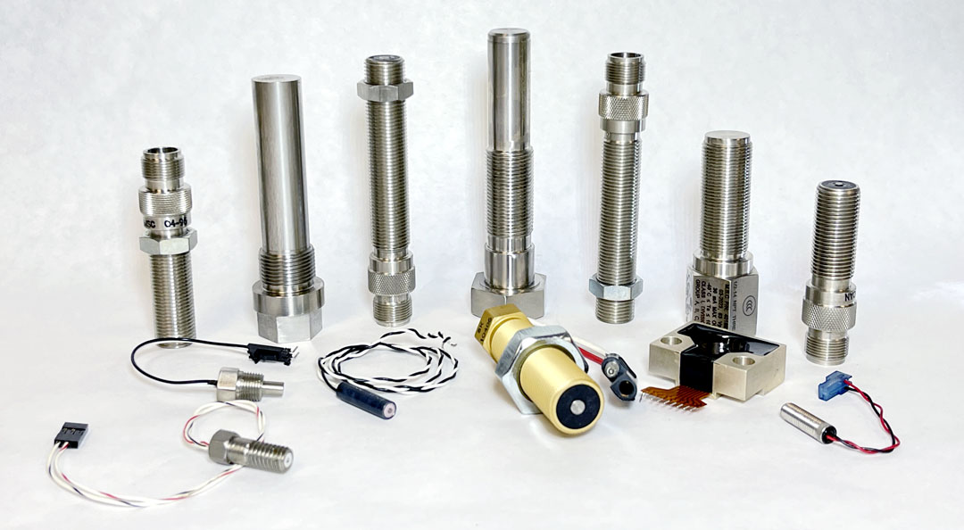 Group shot of various sensors and custom coils manufactured by Magnetic Sensors Corporation, including speed sensors, temperature sensors, and proximity sensors. The components are arranged neatly, showcasing the company's expertise in producing a wide range of sensor technology.